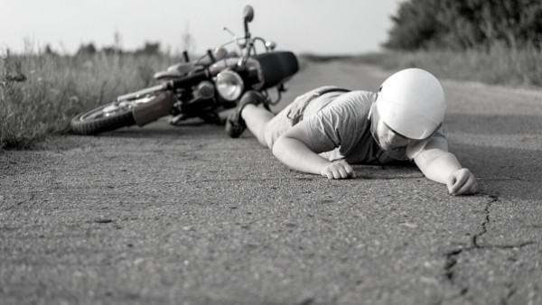 En mann ligger på bakken etter en motorsykkelulykke som hun senere vil kreve erstatning for
