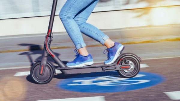 En kvinne som kjører fort med el-sparkesykkel for å rekke møtet