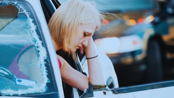 En dame holder seg til hodet etter å ha vært utsatt for en trafikkulykke som hun senere vil kreve menererstatning for