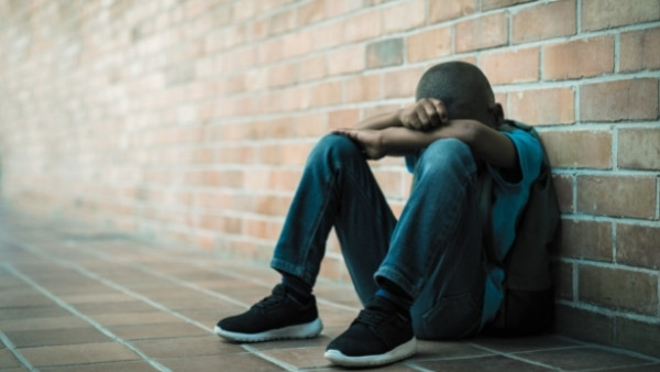 En gutt sitter på gulvet etter å ha vært utsatt for vold på skolen