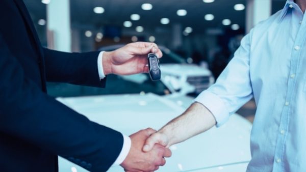 En bilkjøper gir hånden til forhandleren etter kjøp at ny bil