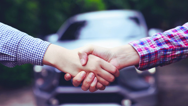 En person som selger bilen sin som privatperson gir hånden til selgeren
