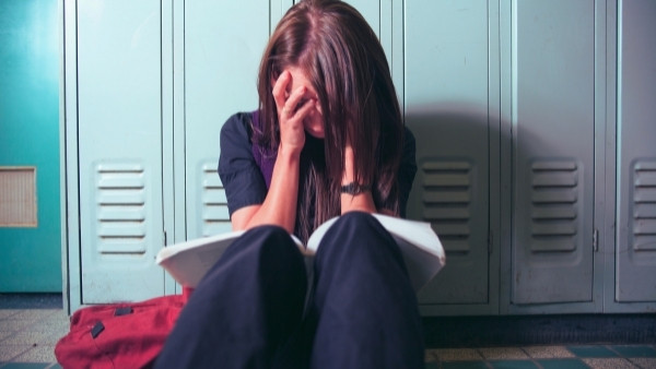 En jente sitter på gulvet etter å ha vært utsatt for vold på skolen